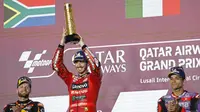 Pembalap Ducati Lenovo, Francesco Bagnaia, mengangkat trofi juara MotoGP Qatar setelah mengungguli Brad Binder dan Jorge Martin di Lusail International Circuit, Senin (11/3/2024) dini hari WIB. (KARIM JAAFAR / AFP)