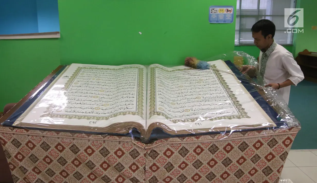 Petugas membersihkan Alquran raksasa yang dipajang di perpustakaan Jakarta Islamic Centre, Jakarta Utara, Jumat (18/5). Alquran ini memiliki ukuran 100 cm x 50 cm dengan berat mencapai 100 kilogram. (Liputan6.com/Arya Manggala)