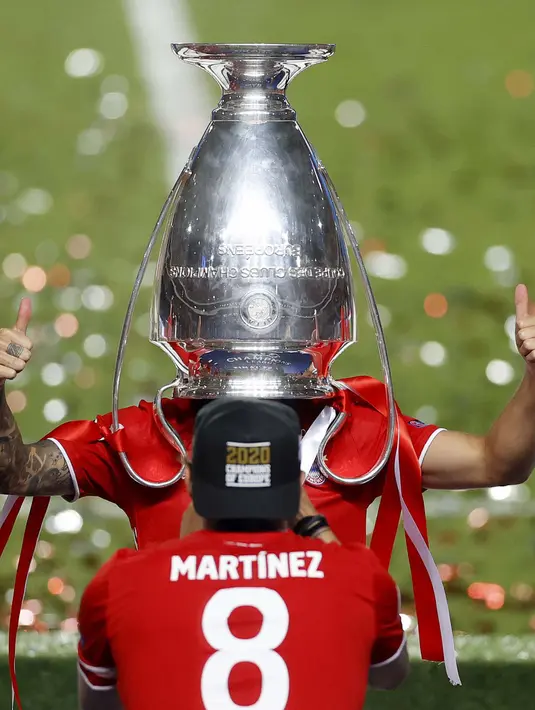 Pemain Bayern Lucas Hernandez menaruh trofi di kepalanya untuk merayakan kemenangan setelah Munich memenangkan pertandingan final Liga Champions antara Paris Saint-Germain dan Bayern Munich di stadion Luz di Lisbon, Portugal, Minggu, (23/8/2020). (Matthew Childs/Pool via AP)