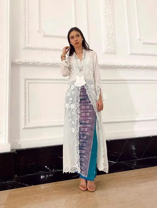 Yuki Kato tampak menawan dengan kebaya encim panjang berwarna putih dipadu kain tenun berwarna biru dan ungu. [Instagram/yukikt]