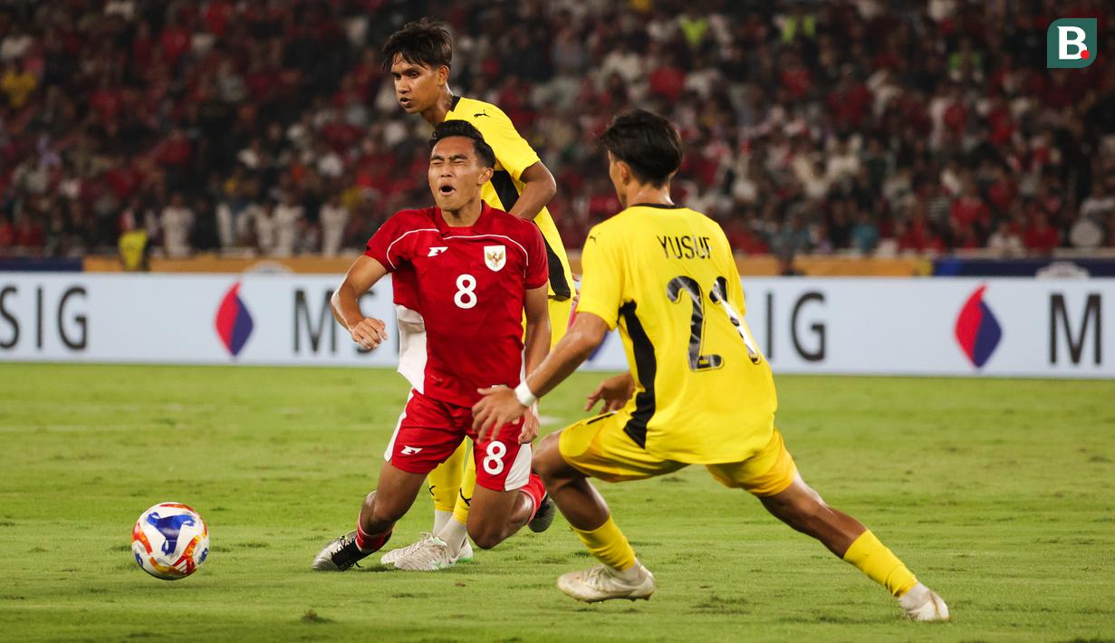 Pemain Timnas Indonesia U-23, Muhammad Rayhan Hannan dijatuhkan pemain Malaysia dalam laga Grup A Piala AFF U-23 2025 di Stadion Utama Gelora Bung Karno (SUGBK), Senayan, Jakarta, Senin (21/07/2025). (Bola.com/Abdul Aziz)