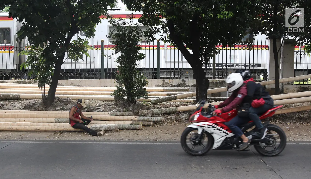 Pengendara melewati pekerja yang sedang mengerjakan pohon pinang di kawasan Tanjung Barat, Jakarta, Kamis (8/8). Penjualan pohon Pinang untuk lomba memanjat memeriahkan peringatan HUT Kemerdekaan RI tersebut mulai marak. (Liputan6.com/Herman Zakharia)