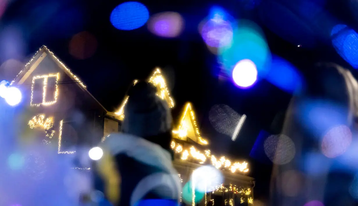 Seorang wisatawan melihat sebuah rumah yang dihiasi lampu Natal di lingkungan Dyker Heights, Brooklyn, New York, Amerika Serikat, 21 Desember 2022. Kawasan Dyker Height terus menghadirkan harapan dan kegembiraan, bahkan dalam masa tersulit sekalipun. (AP Photo/Julia Nikhinson)
