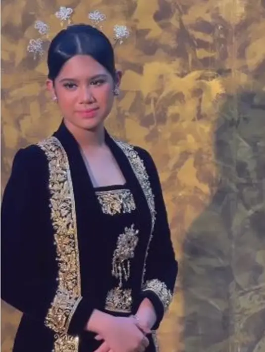 Satu lagi pesona Almira saat mengenakan kebaya. Kali ini, gadis kelahiran tahun 2008 itu tampil begitu anggun saat mengenakan kebaya hitam panjang dengan aksen bordir keemasan. Menampilkan kecantikan khas perempuan Jawa, Almira semakin elegan dengan rambut sanggul dan cunduk mentulnya. (Liputan6.com/IG/@annisayudhoyono)