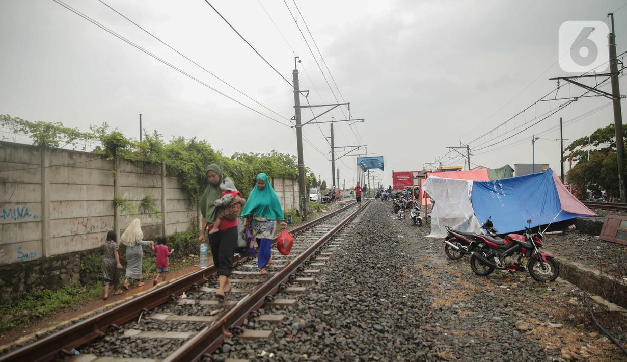 Tenda pengungsi banjir didirikan di jalur rel kereta commuterline Tangerang-Duri di Kembangan Baru, Jakarta, Jumat (3/1/2020). Jalur rel yang nonaktif sementara karena banjir dimanfaatkan warga sekitar untuk mendirikan tenda darurat karena rumah mereka masih terendam. (Liputan6.com/Faizal Fanani)