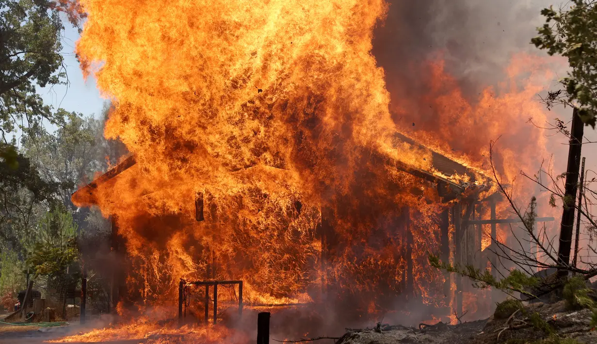 Sebuah rumah terbakar di dekat Mariposa, California(23/7/2022). Api yang bergerak cepat membakar di luar Taman Nasional Yosemite telah memaksa evakuasi, menghanguskan lebih dari 11.500 hektar dan telah menghancurkan beberapa rumah sejak mulai Jumat sore. (Justin Sullivan/Getty Images/AFP)