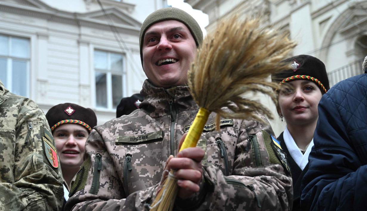 Sebagai informasi, Ukraina secara resmi telah memindahkan perayaan Natal ke tanggal 25 Desember (mulai tahun 2023) untuk memisahkan diri dari pengaruh Rusia. Tampak dalam foto, tentara Ukraina memegang hiasan tradisional 'Didukh' saat mereka mengikuti prosesi Malam Natal di Lviv pada 24 Desember 2025. (YURIY DYACHYSHYN/AFP)
