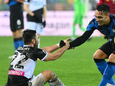 Pemain Inter Milan, Lautaro Martinez (kanan) saat membantu pemain Udinese Tolgay Arslan dalam laga lanjutan Liga Itali 2020/2021 di Friuli stadium, Minggu (24/1/2021) dini hari. (Foto: AFP/Vincenzo Pinto)
