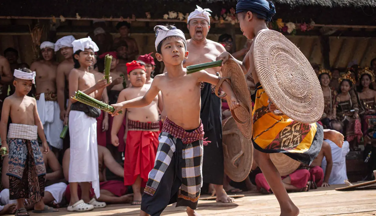 Anak laki-laki mengambil bagian dalam ritual tahunan "Perang Pandan" (pertarungan daun Pandan), yang secara lokal dikenal sebagai "Mekare-kare," untuk menghormati Indra, dewa perang Hindu, di Tenganan Pegringsingan, Bali pada Kamis 11 Juni 2026. (LANA PRIATNA/AFP)