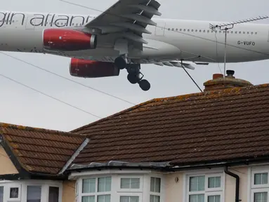 Pesawat Virgin Atlantic terbang rendah dekat atap rumah saat bersiap mendarat di Bandara Heathrow, London, 25 Oktober 2016. Perumahan yang terletak di Myrtle Avenue itu hanya sekitar 91 meter dari landasan Bandara Heathrow. (AP Photo / Frank Augstein)