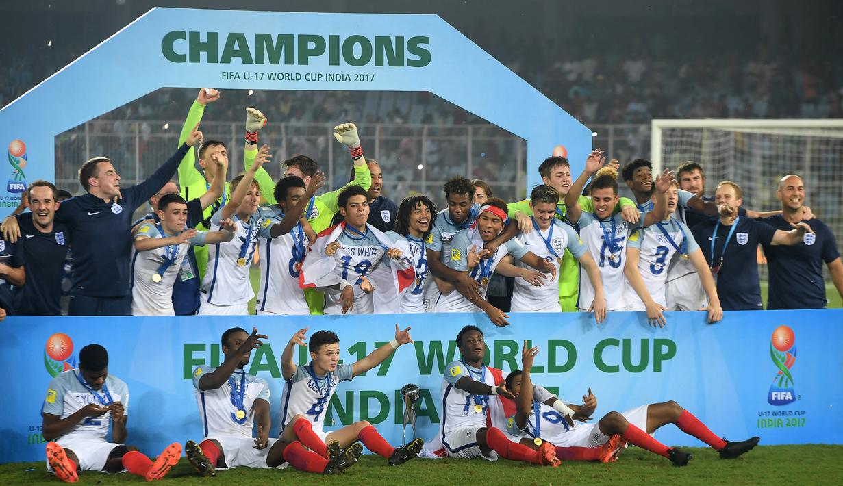 Selebrasi para pemain Inggris dengan medali dan trofi juara setelah mengalahkan Spanyol pada laga final Piala Dunia U-17 2017 di Vivekananda Yuba Bharati Krirangan Stadium, India (28/10/2017. Pada Piala Dunia U-17 2017 yang digelar di India (6-28 Oktober 2017), Inggris sukses menjadi juara setelah mengalahkan Spanyol dengan skor 5-2 di laga final. Lima gol Inggris dicetak oleh Phil Foden (69' dan 88'), Rhian Brewster (44'), Morgan Gibbs-White (58') dan Marc Guehi (84'). Sementara dua gol Spanyol dicetak oleh Sergio Gomez (10' dan 31'). (AFP/Dibyangshu Sarkar)