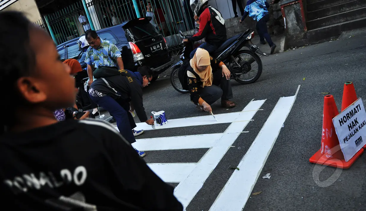 Relawan tergabung dari Koalisi Pejalan Kaki membuat jalur zebra cross di depan Stasiun Sudirman, Jakarta, Jumat (13/3/2015). (Liputan6.com/Faizal Fanani)