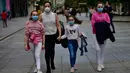 Keluarga mengenakan masker untuk melindungi virus corona berjalan-jalan di promenade Carlos III, di Pamplona, Spanyol utara (27/4/2020). Sebelumnya pemerintah hanya mengizinkan anak-anak keluar rumah untuk menemani orang tua membeli makanan atau obat-obatan. (AP Photo/Alvaro Barrientos)