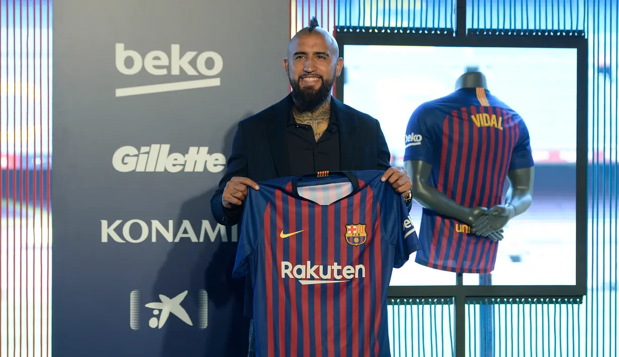 Pemain baru Barcelona, Arturo Vidal menunjukkan jersey Barcelona dalam presentasi resminya di Stadion Camp Nou, Barcelona, Spanyol, Senin (6/8). (Josep LAGO/AFP)