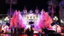 Orang-orang mengunjungi lampu dan dekorasi untuk menyambut Natal yang menghiasi depan Kasino Monte-Carlo di Monako pada 7 Desember 2018. (Photo by VALERY HACHE / AFP)