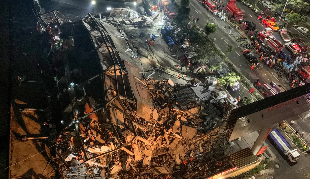 Tim penyelamat mencari korban selamat di puing-puing sebuah hotel yang runtuh di Quanzhou, China, Sabtu (7/3/2020). Sekitar 70 orang terjebak di hotel Xinjia yang akhir-akhir ini digunakan sebagai tempat karantina untuk orang-orang yang berhubungan dengan pasien virus corona. (STR/AFP)