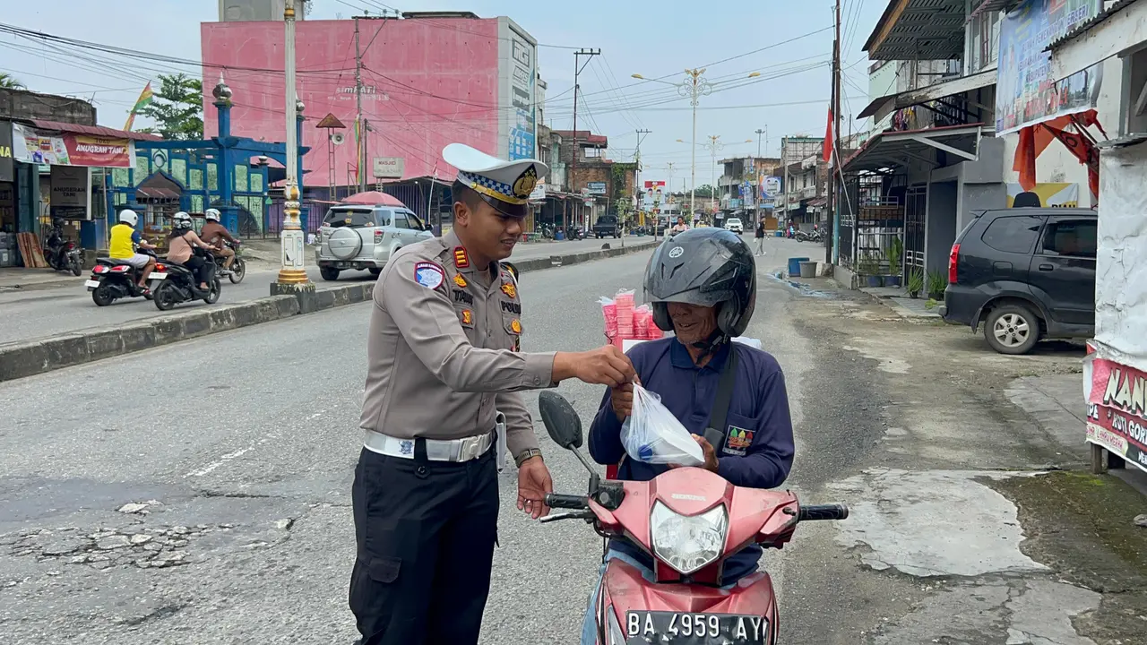 Kasat Lantas Polres Rokan Hulu membagikan nasi kotak kepada pengendara di jalanan.