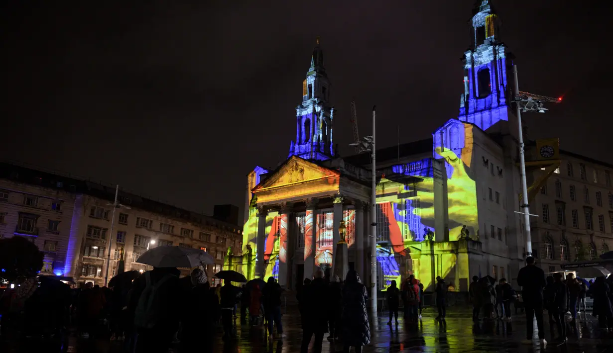 Masyarakat mengagumi instalasi seni bercahaya bertajuk 'Telekinetic Rumours' karya seniman Polandia Pani Pawlosky yang diproyeksikan di Balai Kota Leeds, utara Inggris, 10 Oktober 2019. Festival tersebut menampilkan proyeksi, instalasi interaktif, eksebisi, dansa, dan musik. (Oli SCARFF/AFP)