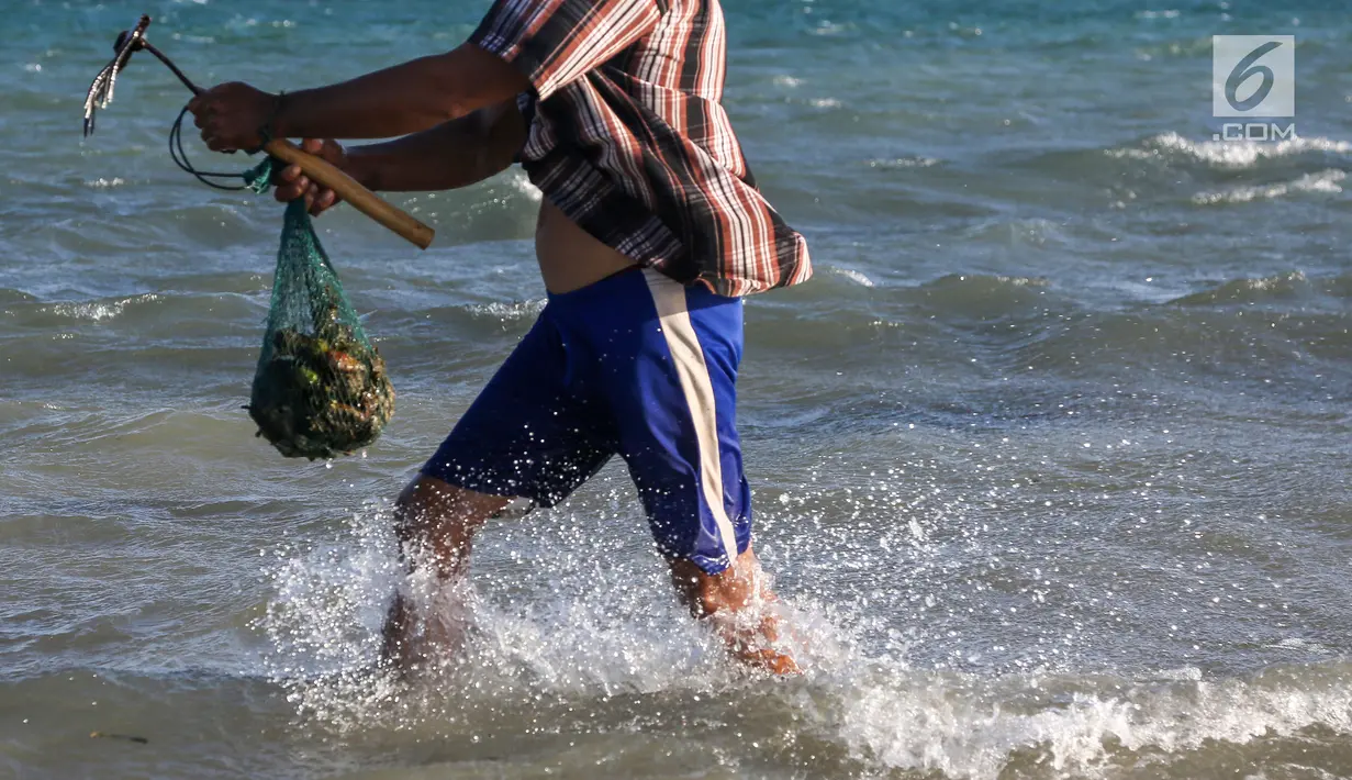 Warga berjalan membawa hasil tangkapan kerang di pesisir pantai Pulau Pasir, Lombok Timur, Sabtu (3/8/2019). Mereka mulai menangkap kerang ketika Pulau Pasir yang membentang laut akan tampak ketika air laut surut. (Liputan6.com/Fery Pradolo)