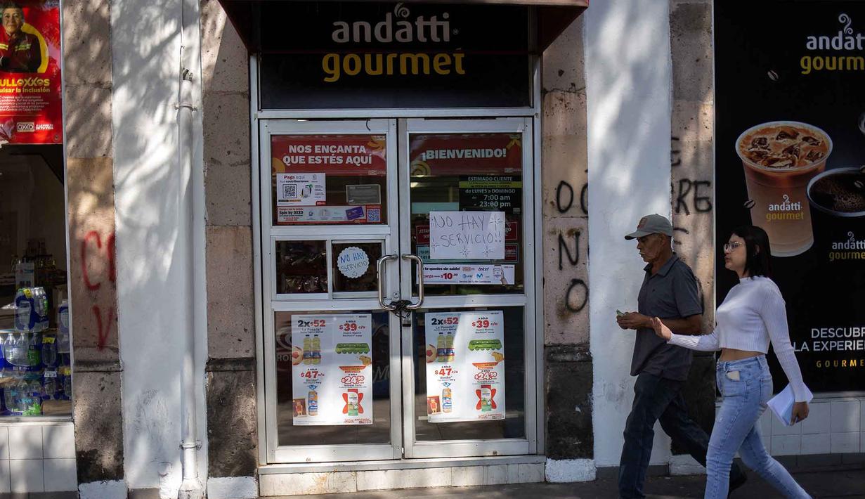 Sebagai informasi, Pemimpin Cartel Jalisco Nueva Generacion (CJNG), Nemesio Ruben Oseguera Cervantes alias "El Mencho", ini tewas pada Minggu 22 Februari 2026 setelah terluka dalam baku tembak dengan militer di Tapalpa, Jalisco, Meksiko. Tampak dalam foto, orang-orang berjalan melewati toko yang tutup dengan tanda bertuliskan "Tidak ada layanan" di Morelia, negara bagian Michoacan, Meksiko, pada 23 Februari 2026. (Enrique Castro/AFP)