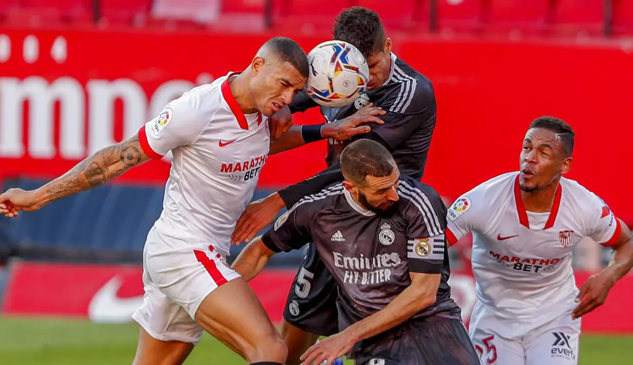 Bek Real Madrid, Raphael Varane, berebut bola dengan pemain Sevilla, Diego Carlos, pada laga Liga Spanyol di Stadion Ramon Sanchez Pizjuan, Minggu (6/12/2020). Real Madrid menang dengan skor 1-0. (AP/Angel Fernandez)
