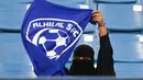 Seorang wanita mengibarkan bendera saat mendukung tim Al-Hilal dari Saudi melawan Al-Ittihad dalam pertandingan Liga Saudi Pro di King Fahd International Stadium di Riyadh (13/1). (AFP Photo/Ali Al-Arifi)