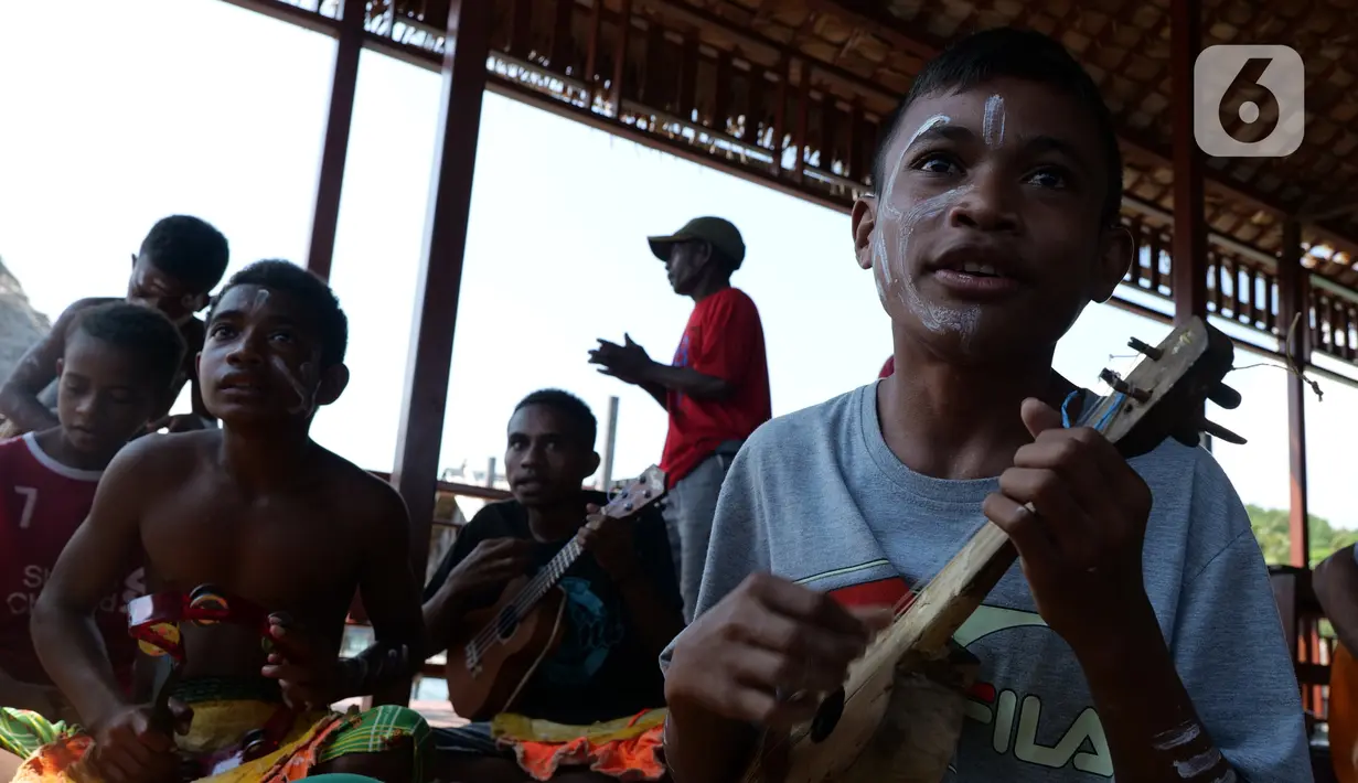 Seorang anak memainkan alat musik saat mengikuti latihan tari di rumah seni Sawinggrai, Raja Ampat, Papua Barat, Jumat (22/11/2019). Pertamina melalui program tanggung jawab sosialnya membangun Rumah Seni Budaya Sawinggrai pada tahun 2016. (Liputan6.com/Herman Zakharia)