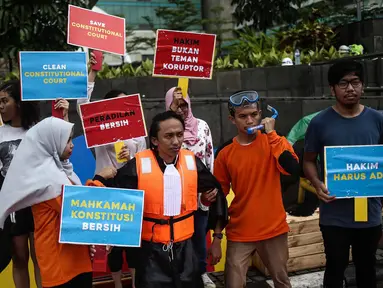 Sejumlah orang yang tergabung dalam Indonesia Corruption Watch (ICW) menggelar aksi teatrikal saat Car Free Day dikawasan Bunderan HI, Jakarta, Minggu (12/2). Aksi tersebut bertajuk 'Selamatkan Mahkamah Konstitusi'. (Liputan6.com/Faizal Fanani)