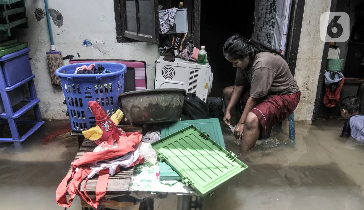 Warga mencuci pakaian saat banjir merendam permukiman warga di kawasan Kemang Timur XI, Jakarta Selatan, Minggu (21/2/2021). Warga berharap pemerintah segera memperbaiki longsor agar banjir tidak berkepanjangan. (merdeka.com/Iqbal S. Nugroho)