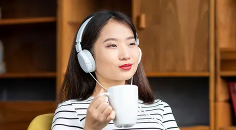 perempuan minum kopi mendengarkan musik