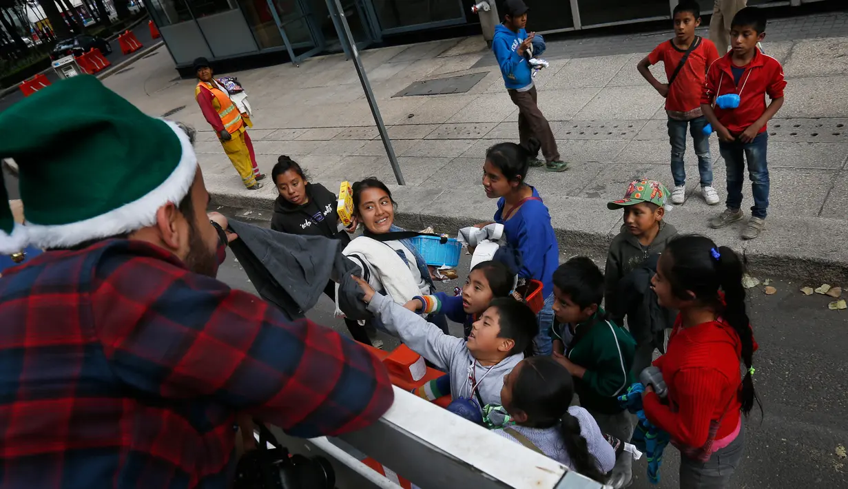 Juan Carlos Ascencio membagikan pakaian dan mainan sebagai hadiah Natal kepada anak-anak tidak mampu di jalanan Mexico City, Meksiko (23/12). (AP Photo / Marco Ugarte)