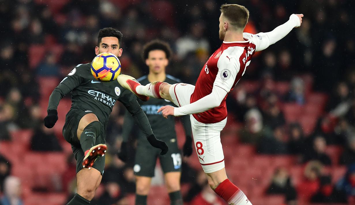 Gelandang Arsenal, Aaron Ramsey, berebut bola dengan gelandang Manchester City, Ilkay Gundogan, pada laga Premier League di Stadion Emirates, London, Kamis (1/3/2018). Arsenal kalah 0-3 dari City. (AFP/Glyn Kirk)