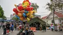 Masyarakat dapat melihat langsung dari dekat dan berfoto dengan alutsista tersebut. Tampak dalam foto, seorang penjual balon menunggu pelanggan sementara pengunjung berfoto dengan kendaraan militer selama Pameran Marinir Indonesia, yang menandai peringatan Hari Ulang Tahun ke-80 Korps Marinir TNI AL di Surabaya, Jawa Timur pada Minggu 9 November 2025. (JUNI KRISWANTO/AFP)