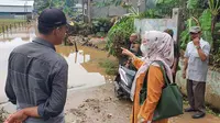 Anggota DPRD Kota Depok, Yuni Indriani meninjau lokasi banjir di Jalan mawar RW4, Kelurahan Pasir Putih, Kecamatan Sawangan, Kota Depok, telah menyurut pasca banjir luapan Kali Pesanggrahan. (Liputan6.com/Dicky Agung Prihanto)