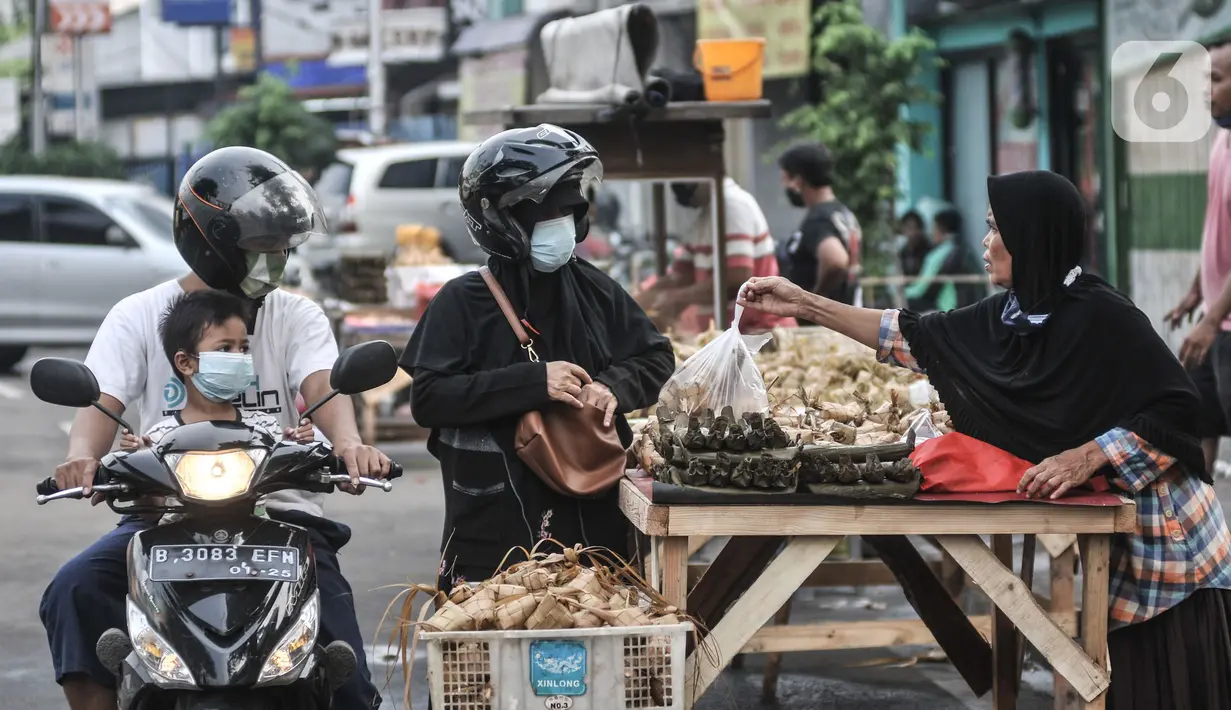 Pedagang melayani pembeli ketupat matang di jalan kawasan Rawamangun, Jakarta, Senin (19/7/2021). Jelang Hari Raya Idul Adha, pedagang ketupat matang atau siap saji musiman mulai ramai menjajakan makanan khas Lebaran tersebut di pinggir jalan kawasan Rawamangun. (merdeka.com/Iqbal S. Nugroho)