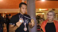 I Gede Siman Sudartawa memamerkan medali SEA Games disaksikan sang ibu, Ni Made Sri Kardini. (Liputan6.com/Dewi Divianta)