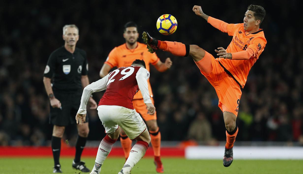 Gelandang Liverpool, Roberto Firmino, berebut bola dengan gelandang Arsenal, Granit Xhaka, pada laga Premier League di Stadion Emirates, London, Jumat (22/12/2017). Kedua klub bermain imbang 2-2. (AFP/Ian Kington)