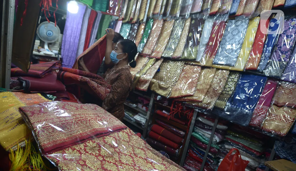 Aktivitas jual beli kain ulos di pasar proyek Senen, Jakarta, Kamis (21/10/2021). Sejak status PPKM turun dari level 3 menjadi level 2, pengunjung ramai mendatangi toko membeli kain ulos untuk upacara pernikahan adat dengan kisaran harga dari Rp. 500.000 hingga jutaan rupiah. (merdeka.com/Imam Buhor