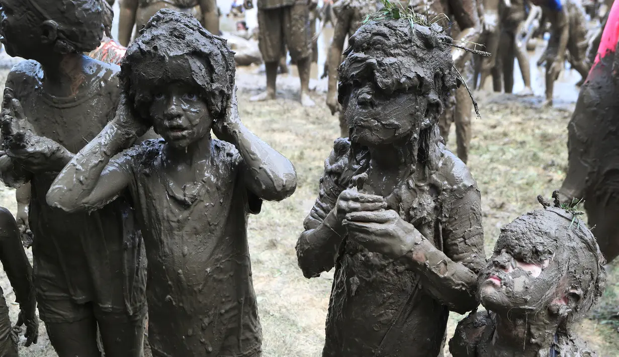 Anak-anak perempuan dipenuhi lumpur setelah bermain pada perayaan Mud Day atau Hari Lumpur Tahunan di Westland, Michigan, AS, Selasa (10/7). Dalam Mud Day kali ini para pesertanya yang ikut adalah anak-anak.  (AP/Carlos Osorio)