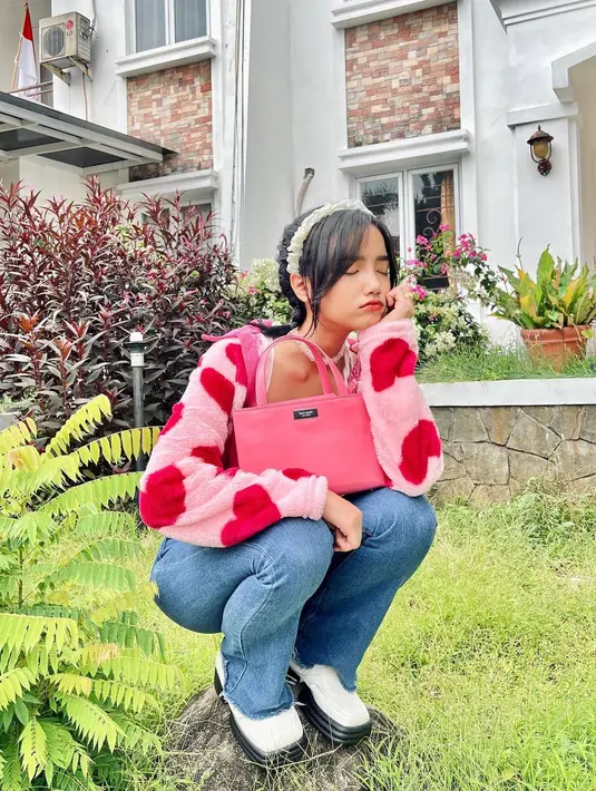 Penampilan lebih semarak dari Fuji mengenakan padu padan celana jeans. Sweater bermotif hati bernuansa merah-merah muda dipadunya dengan celana jeans panjang, serta diberi pemanis bando putih untuk aksesori rambut. Foto: Instagram.