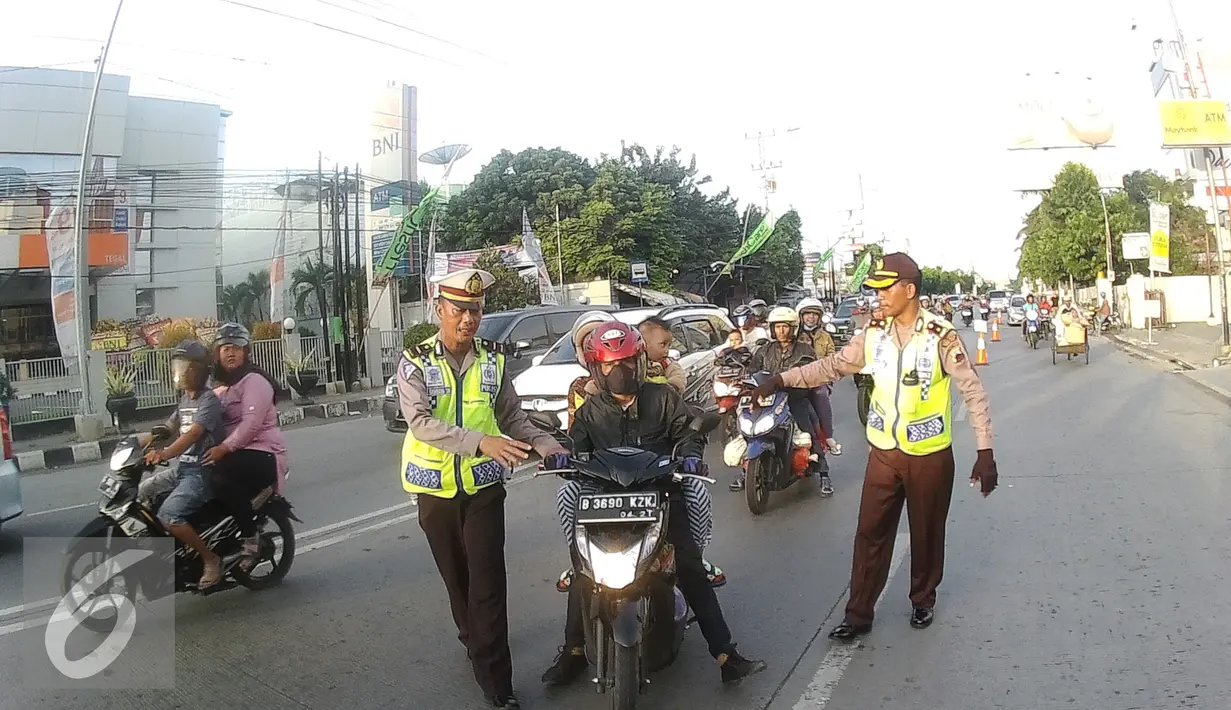 Petugas Kepolisian memberhentikan pengendara motor yang membawa balita di Simpang Maya, Tegal, Jawa Tengah Minggu (10/7). Petugas menghimbau untuk memberikan keamanan yang layak untuk anak saat berkendara. (Liputan6.com/Herman Zakharia)