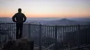 Seorang pejalan kaki melihat pemandangan kota Seoul dan menara Namsan selama matahari terbit di Korea Selatan (31/10). Kota ini adalah pusat politik, budaya, sosial dan ekonomi di Korea Selatan dan Asia Timur. (AFP Photo/Ed Jones)