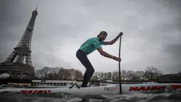 Peserta Nautic Paddle Race atau lomba dayung sambil berdiri melintas dekat Menara Eiffel di Sungai Seine, Paris, Minggu (8/12/2019). Sekitar 1000 pesaing ikut serta dalam lomba sejauh 11 kilometer menyeberangi sungai Seine dengan pemandangan kota Paris. (Photo by Olivier MORIN / AFP)