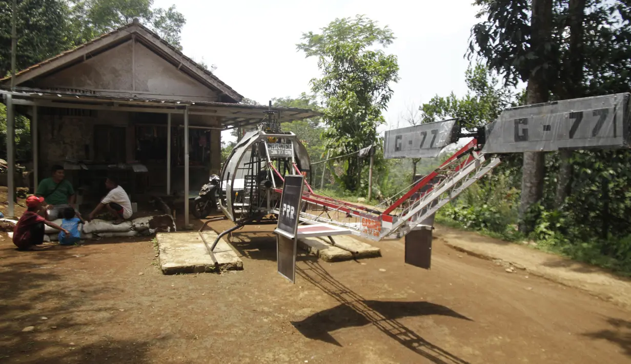 Gambar yang diambil pada 17 November 2019, Jujun Junaedi duduk di dekat helikopter buatannya di halaman belakang rumahnya di Sukabumi. Jujun merogoh kocek hingga lebih dari RP 30 juta rupiah untuk merakit helikopter bermesin genset dua silinder 700 cc ini. (Wulung WIDARBA/AFP)