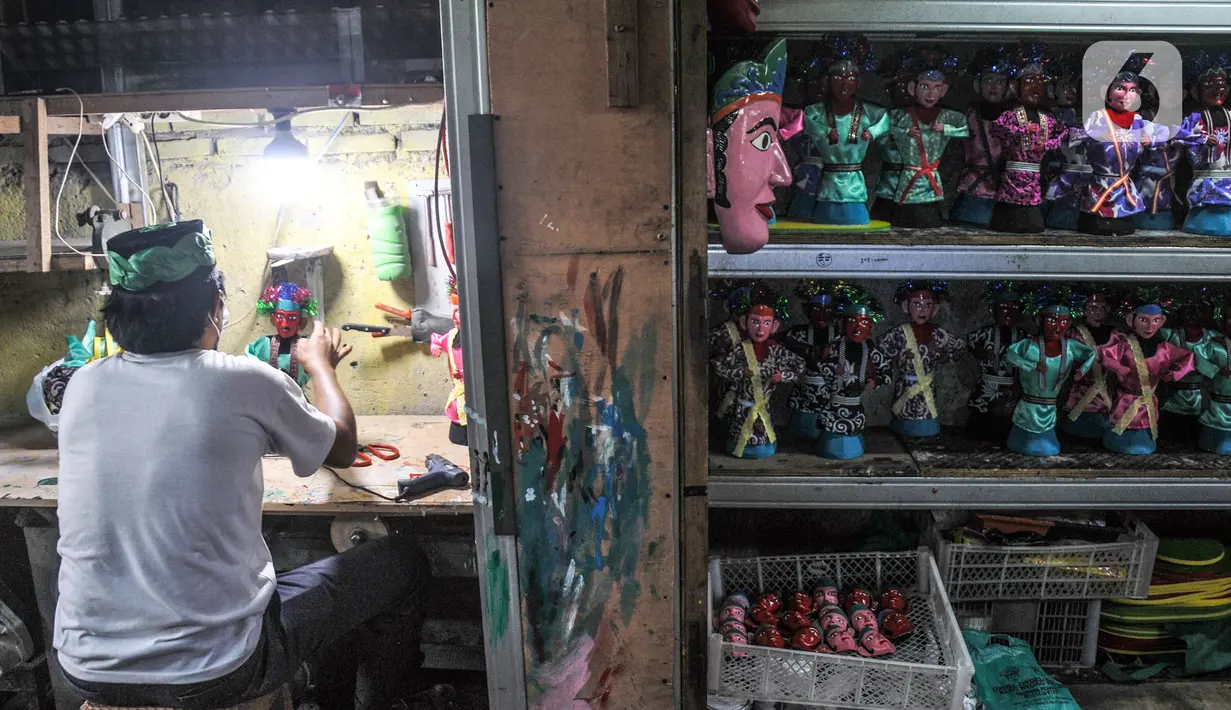 Masudi alias Bang Ntong Salam (40) menyelesaikan pembuatan miniatur ondel-ondel di Jalan Gang 3, Kelurahan Pondok Kopi, Kecamatan Duren Sawit, Jakarta Timur, Selasa (19/10/2021). Meski sempat terhenti akibat pandemi, Bang Ntong perlahan bangkit membuat ondel-ondel mini.(merdeka.com/Iqbal S. Nugroho)