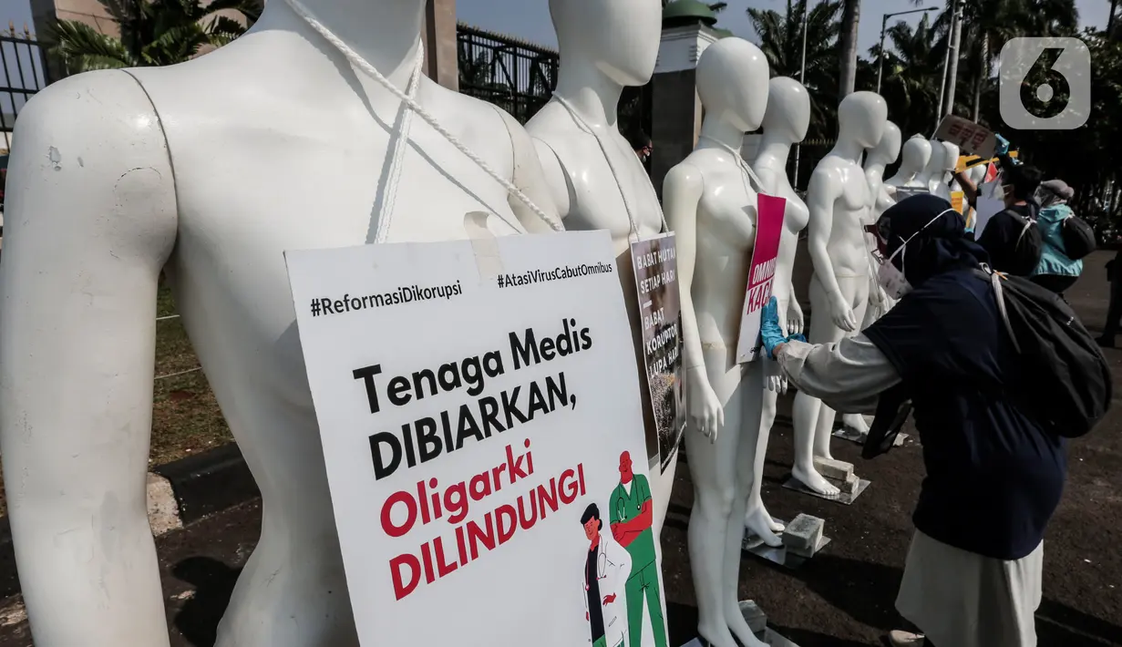 Aktivis Greenpeace Indonesia memasang poster pada puluhan maneken saat menggelar aksi damai di depan gerbang kompleks DPR, Jakarta Pusat, Senin (29/6/2020). Aksi tersebut dilakukan sebagai bentuk penolakan terhadap RUU Omnibus Law. (Liputan6.com/Johan Tallo)