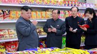 Pemimpin Korea Utara, Kim Jong-un berbincang dengan stafnya ketika berada di toko makanan saat mengunjungi Taesong Department Store setelah dibuka untuk umum di Korea Utara (8/4). (KCNA VIA AFP Photo)