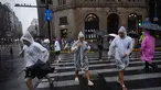 Orang-orang melindungi diri mereka dengan mantel hujan sekali pakai selama perjalanan Topan Co-May di Shanghai pada tanggal 30 Juli 2025. (Hector RETAMAL/AFP)