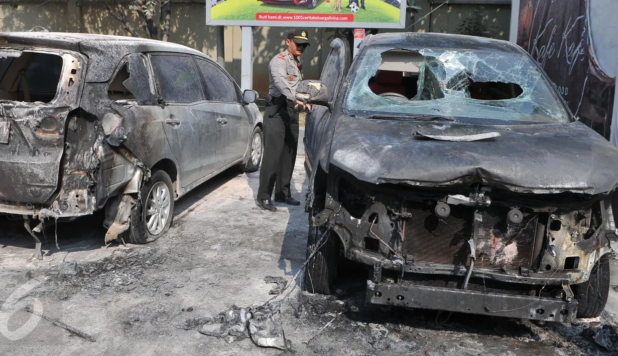 Seorang polisi saat memeriksa kondisi mobil yang terbakar di area SPBU Jalan Gatot Subroto, Jakarta, Selasa (1/9/2015). Sumber api diduga berasal dari sebuah drum yang berada di dekat tangki pengisian BBM di SPBU tersebut. (Liputan6.com/Herman Zakharia)