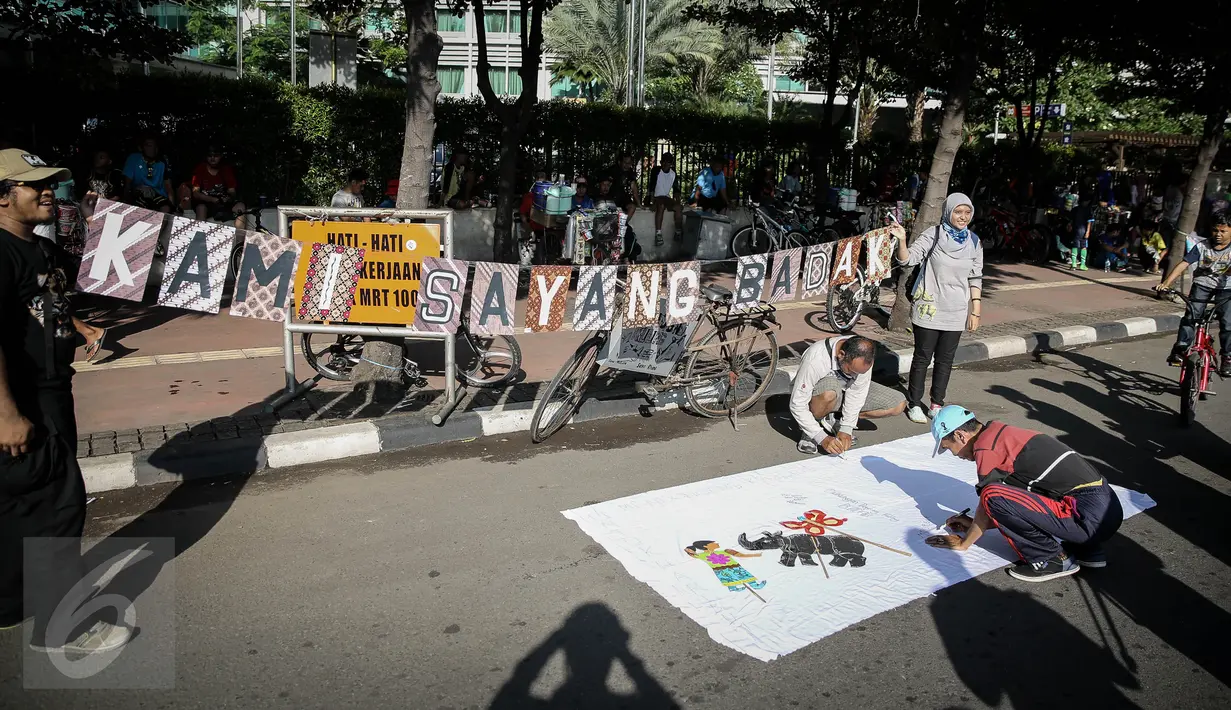 Warga menandatangani kain putih sebagai dukungan saat aksi 'Kami Sayang Badak' pada Car Free Day di kawasan Bunderan HI, Jakarta, (27/3). Aksi tersebut guna Memperingati hari bumi dan kampanye Badak yang hampir punah. (Liputan6.com/Faizal Fanani)